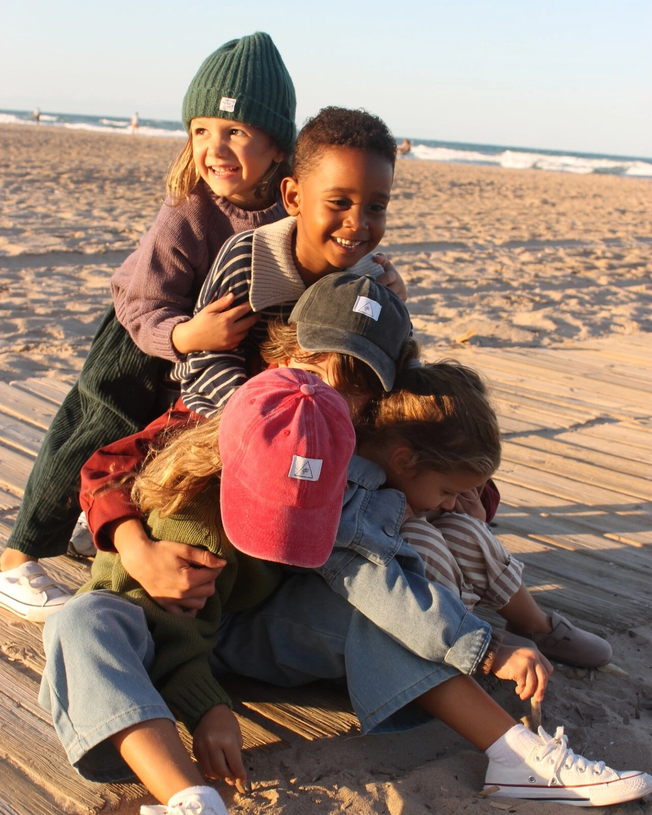 Niños jugando juntos en la playa con prendas de Attic Kids