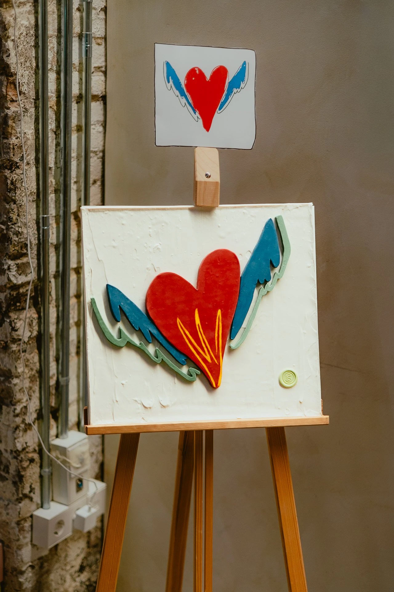 El corazón alado de Guïnda expuesto junto a su ilustración